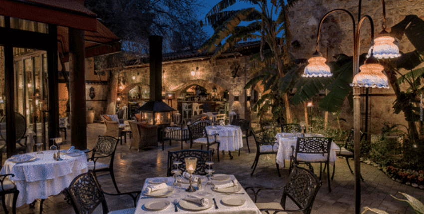 Restaurant extérieur au crépuscule, éclairé par des lumières chaudes.