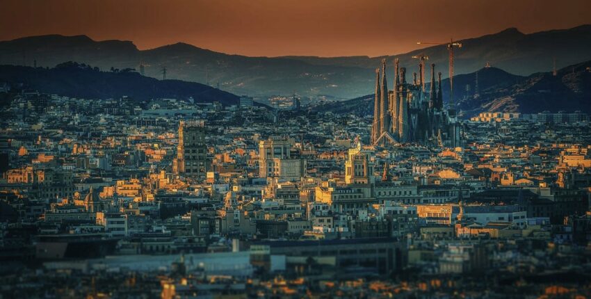 location jet privé : Coucher de soleil sur un paysage urbain avec une cathédrale et des grues proéminentes.