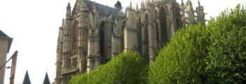 location de jet privé : Cathédrale gothique, arbres et ciel nuageux.