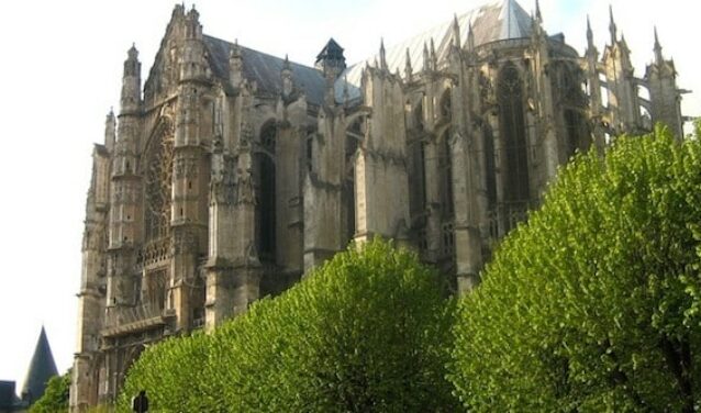 location de jet privé : Cathédrale gothique, arbres et ciel nuageux.