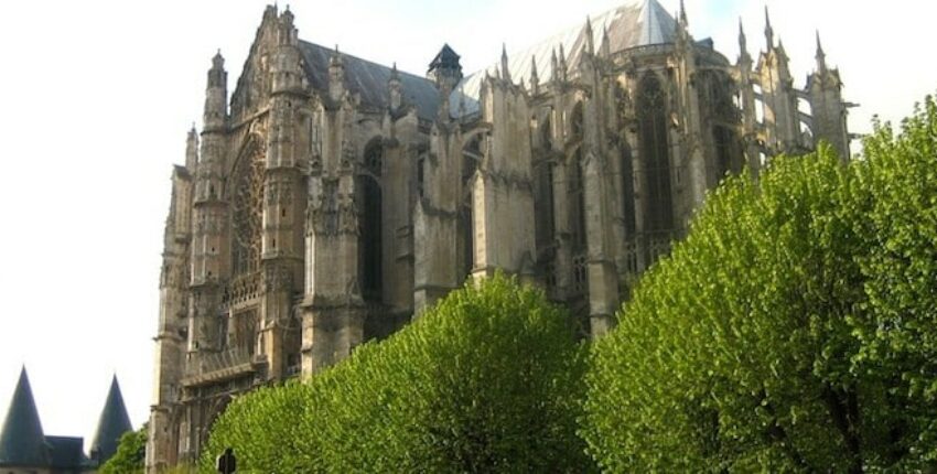 location de jet privé : Cathédrale gothique, arbres et ciel nuageux.