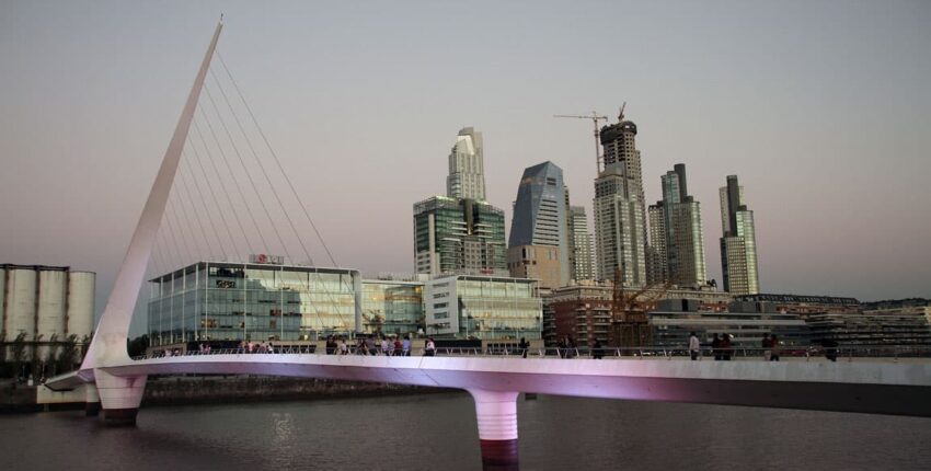 Pont blanc moderne sur l'eau avec skyline en arrière-plan.