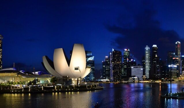 Singapour : Marina Bay de nuit avec gratte-ciels illuminés.