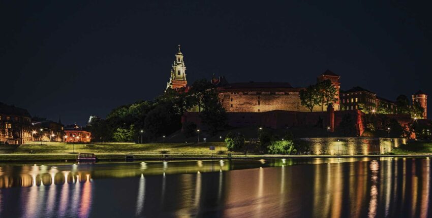 Château au bord de la rivière reflété sur l'eau calme la nuit.