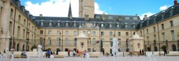 **Texte original :**
Les gens se promènent près d'un bâtiment historique avec une tour d'horloge et une cour ornée de fontaines, sous un ciel bleu, à Dijon Bourgogne. C’est le cadre idéal pour ceux qui arrivent par location de jet privé.

**Nouveau texte :**
_Dijon Bourgogne_, promenade près du bâtiment historique.