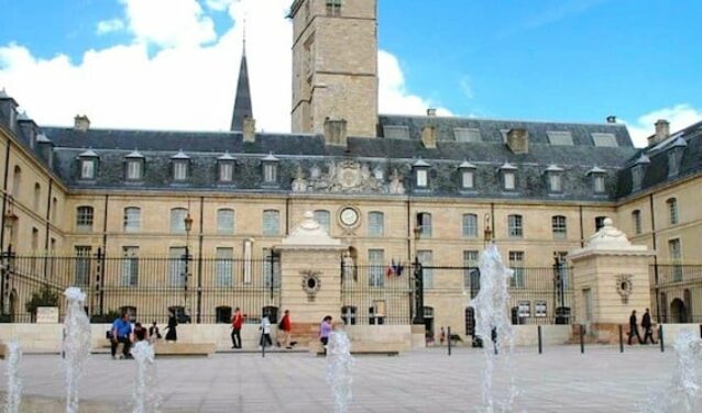 **Texte original :**
Les gens se promènent près d'un bâtiment historique avec une tour d'horloge et une cour ornée de fontaines, sous un ciel bleu, à Dijon Bourgogne. C’est le cadre idéal pour ceux qui arrivent par location de jet privé.

**Nouveau texte :**
_Dijon Bourgogne_, promenade près du bâtiment historique.