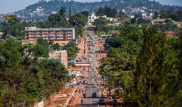 Rue animée de Kampala avec collines et ciel dégagé.