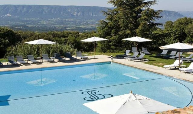 Hôtel Les Bories : piscine extérieure, chaises longues, montagnes.