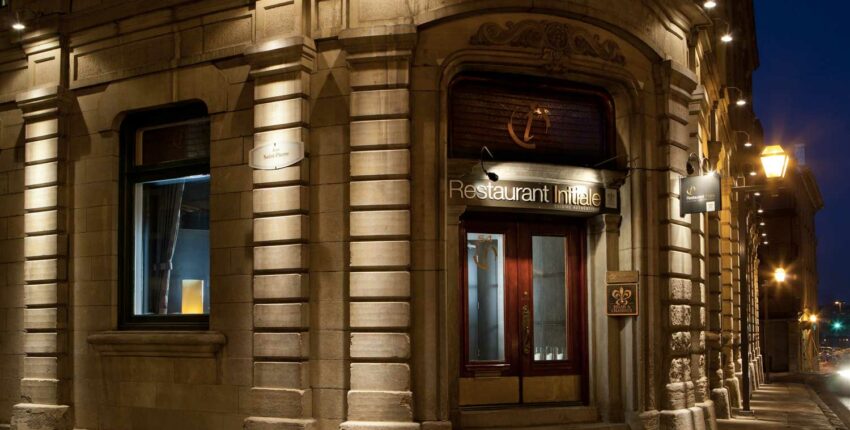 Entrée restaurant gastronomique nocturne, façade éclairée.