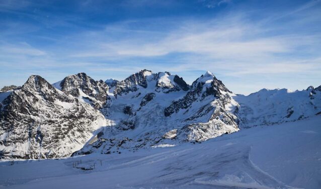 Saint-Moritz - Samedan, montagnes enneigées, ciel bleu clair.