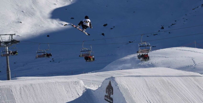 Snowboarder sautant en l'air sur une rampe enneigée.