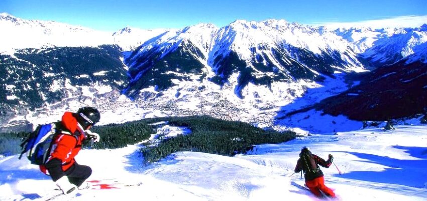 Deux skieurs dévalent une montagne enneigée.