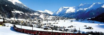 Train rouge, montagnes enneigées, ciel bleu, Klosters.