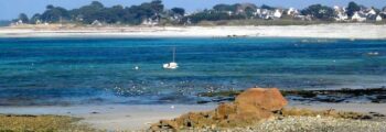 Plage rocheuse, bateau amarré, eau turquoise près de Lannion.