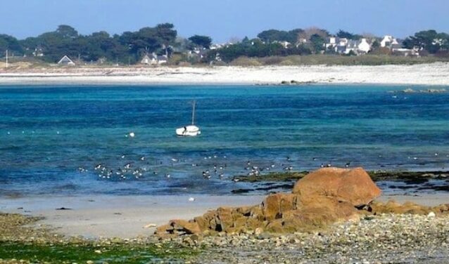 Plage rocheuse, bateau amarré, eau turquoise près de Lannion.