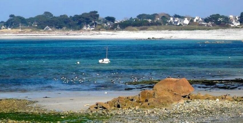 Plage rocheuse, bateau amarré, eau turquoise près de Lannion.