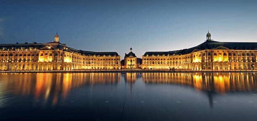 Monument éclairé reflétant sur l'eau à Bordeaux, France