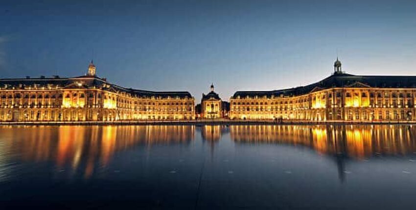 Monument éclairé reflétant sur l'eau à Bordeaux, France