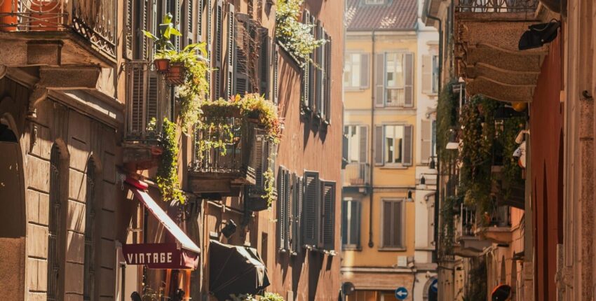 Milan Linate, rue ensoleillée avec motos et balcons.