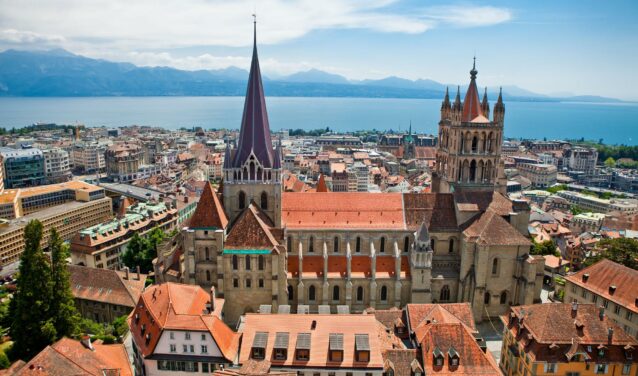 Vue aérienne Cathédrale de Lausanne, toits rouges, lac, montagnes.