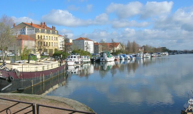 Vue panoramique Roanne, rivière calme, bateaux à quai, journée ensoleillée.