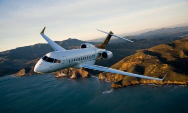 Le jet privé Bombardier Global 6000 en vol avec un couché de soleil, la mer et des montages