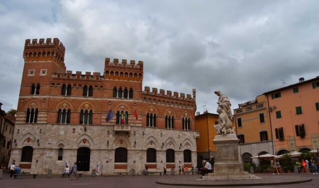 Grosseto, bâtiment historique avec statue et drapeaux.