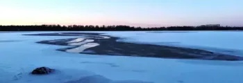 Vaxjo Urasa : lac enneigé, ciel clair, arbres.