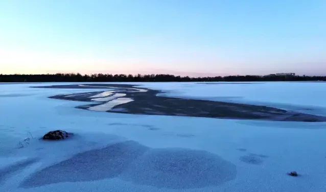 Vaxjo Urasa : lac enneigé, ciel clair, arbres.