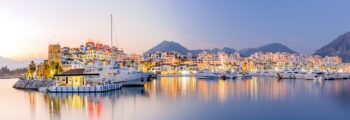 Marina de Puerto Banus au crépuscule, yachts amarrés, toile de fond de montagne.