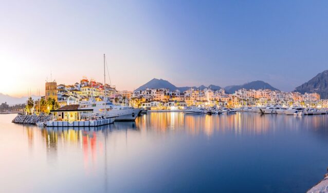 Marina de Puerto Banus au crépuscule, yachts amarrés, toile de fond de montagne.