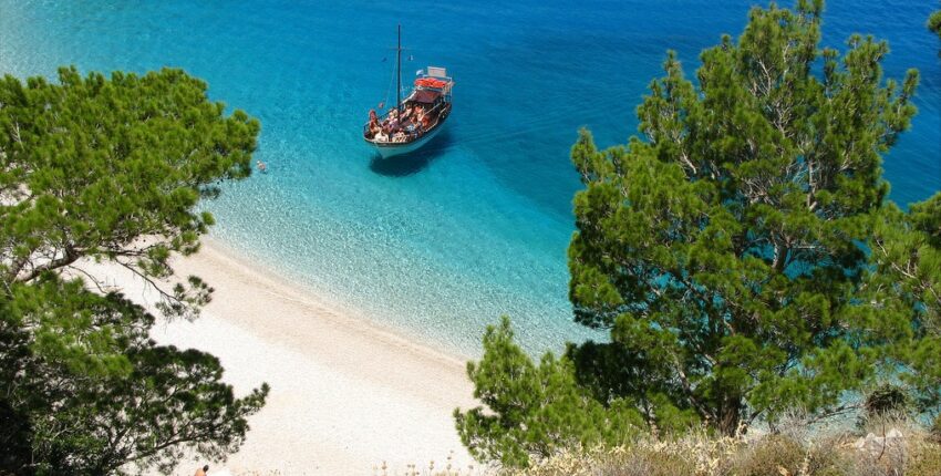 location de jet privé : Plage sereine, bateau rustique abordant l'île