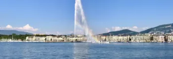 Fontaine éclairée devant bâtiment majestueux au crépuscule.